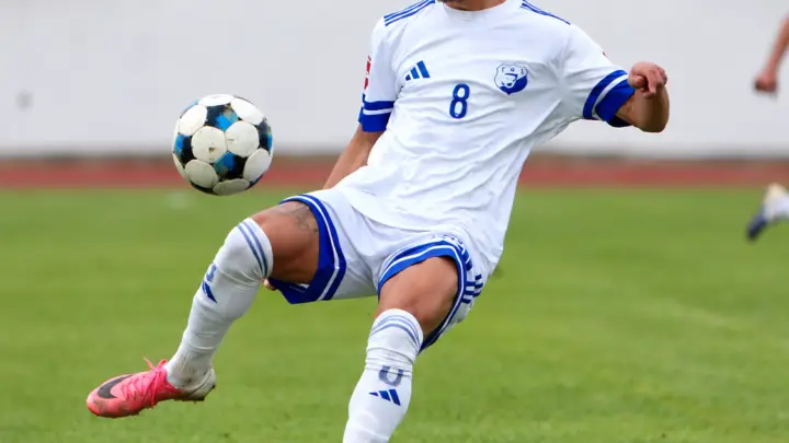 Fudbaler Jedinstva Franca u bijelo-plavom dresu kontroliše loptu; fotografija dostavljena sa klupskog Instagram profila i grafički obrađena bez rezultatskih oznaka. Jedinstvo – Kom 1:2.