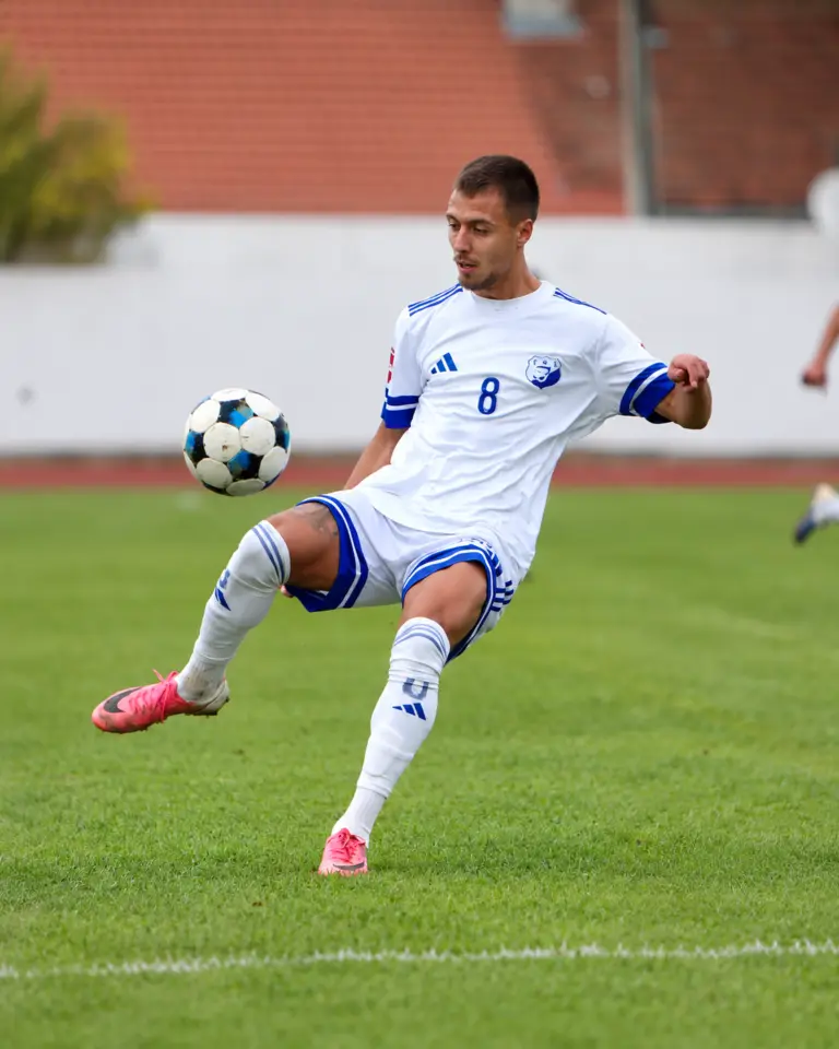 Fudbaler Jedinstva Franca u bijelo-plavom dresu kontroliše loptu; fotografija dostavljena sa klupskog Instagram profila i grafički obrađena bez rezultatskih oznaka. Jedinstvo – Kom 1:2.